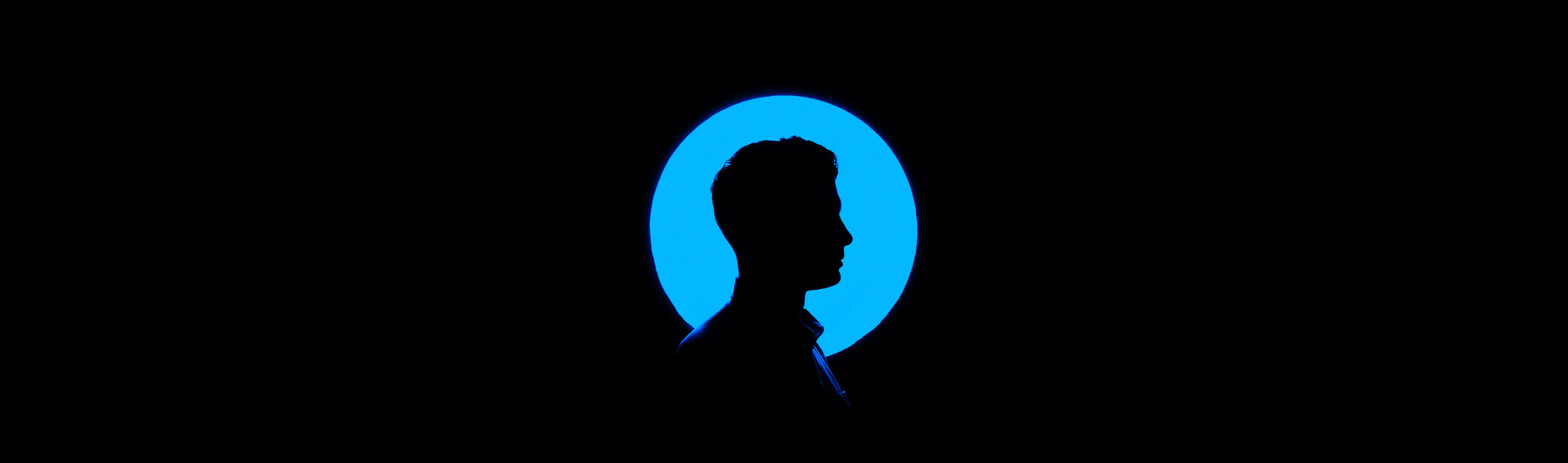 Dark silhouette of man in front of blue circle